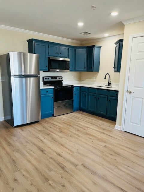 A modern kitchen with blue cabinets and stainless steel appliances.
