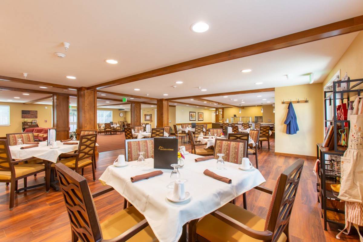 A well-lit restaurant dining area with neatly arranged tables and chairs, featuring elegant table settings.