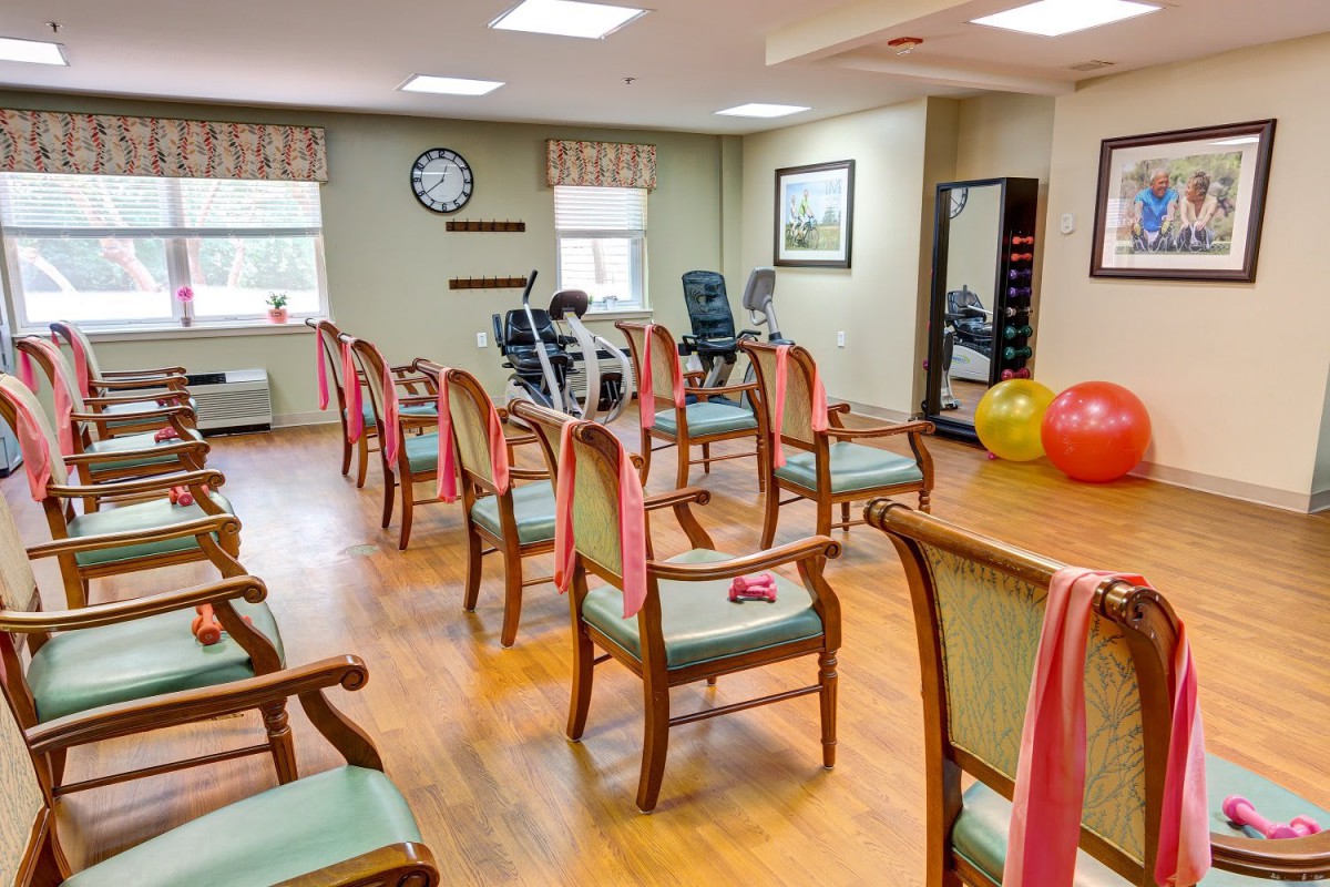 An exercise room with chairs arranged for group activities, featuring fitness equipment and exercise balls.