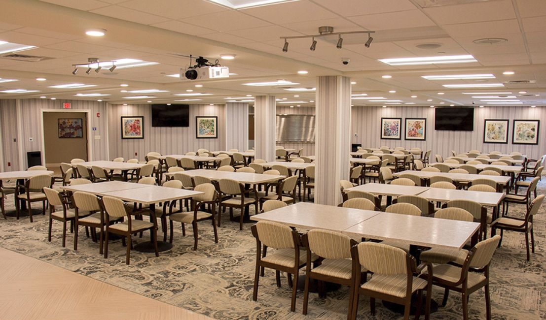 An empty cafeteria with neatly arranged tables and chairs, well-lit interior.
