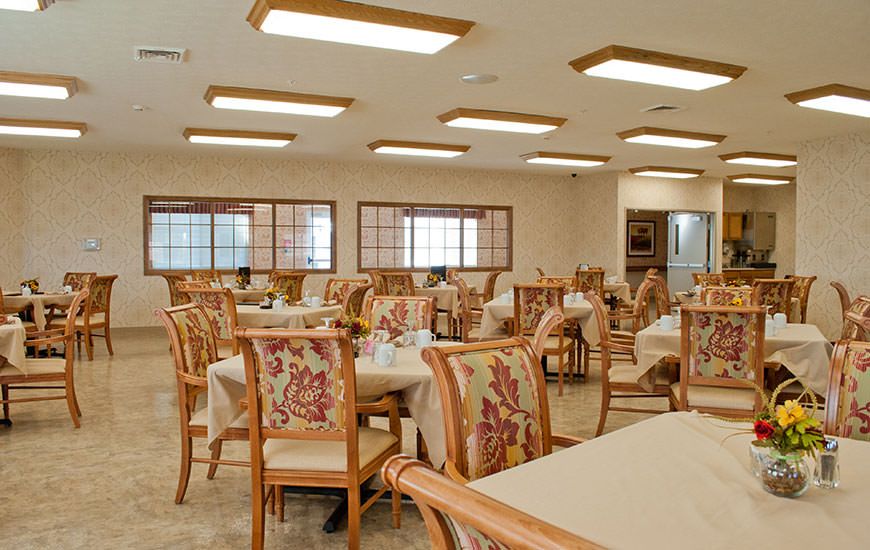An empty dining hall with neatly arranged tables and chairs.