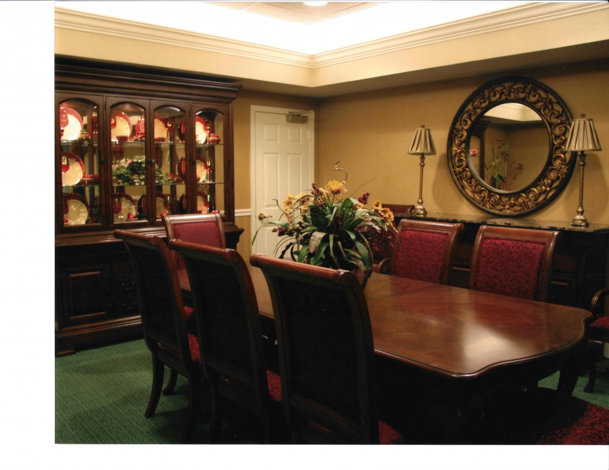 A sophisticated dining room with a large wooden table surrounded by chairs, featuring elegant decor and soft lighting.