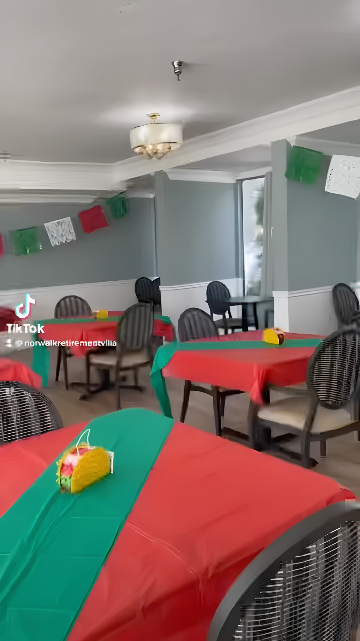 A decorated restaurant with colorful tablecloths and festive flags hanging from the ceiling.