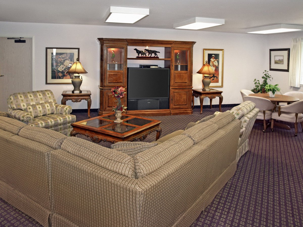 A cozy living room featuring a wrap-around sofa, wooden entertainment center, and elegant lighting.