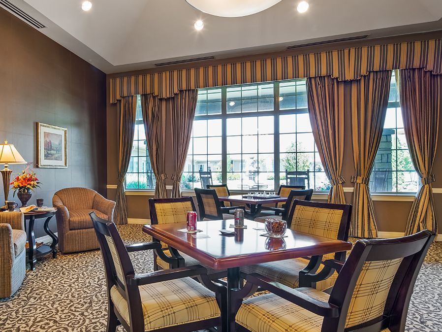 A cozy lounge area with a table and chairs, featuring large windows and elegant curtains.