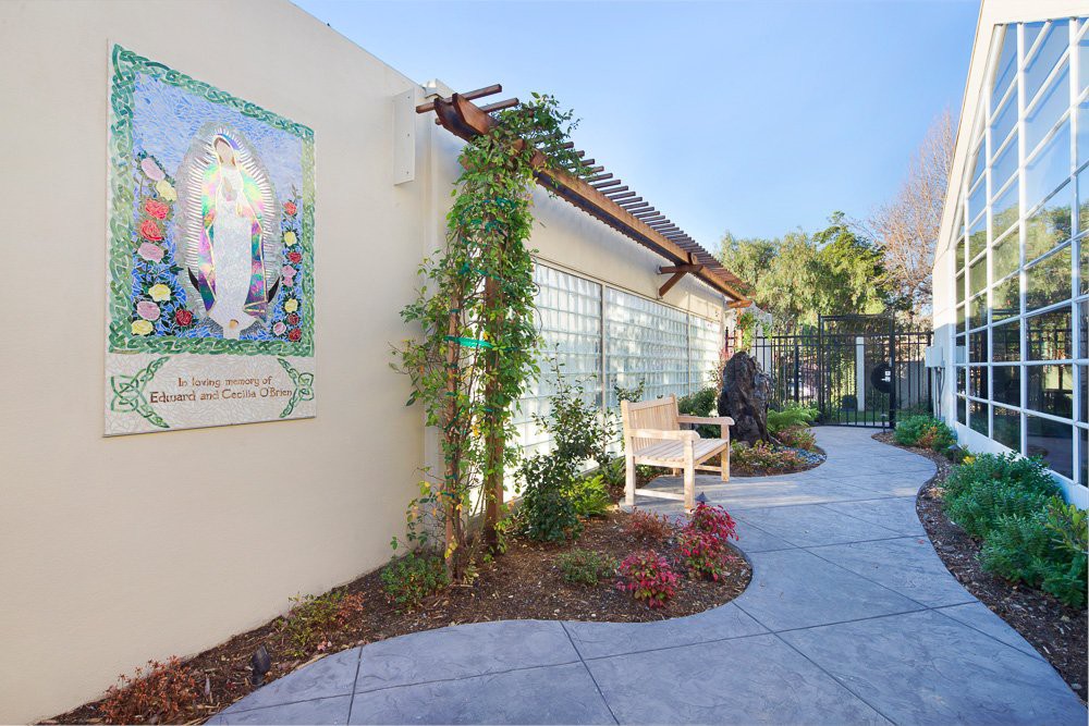 A well-maintained garden path with a bench and greenery alongside a building.