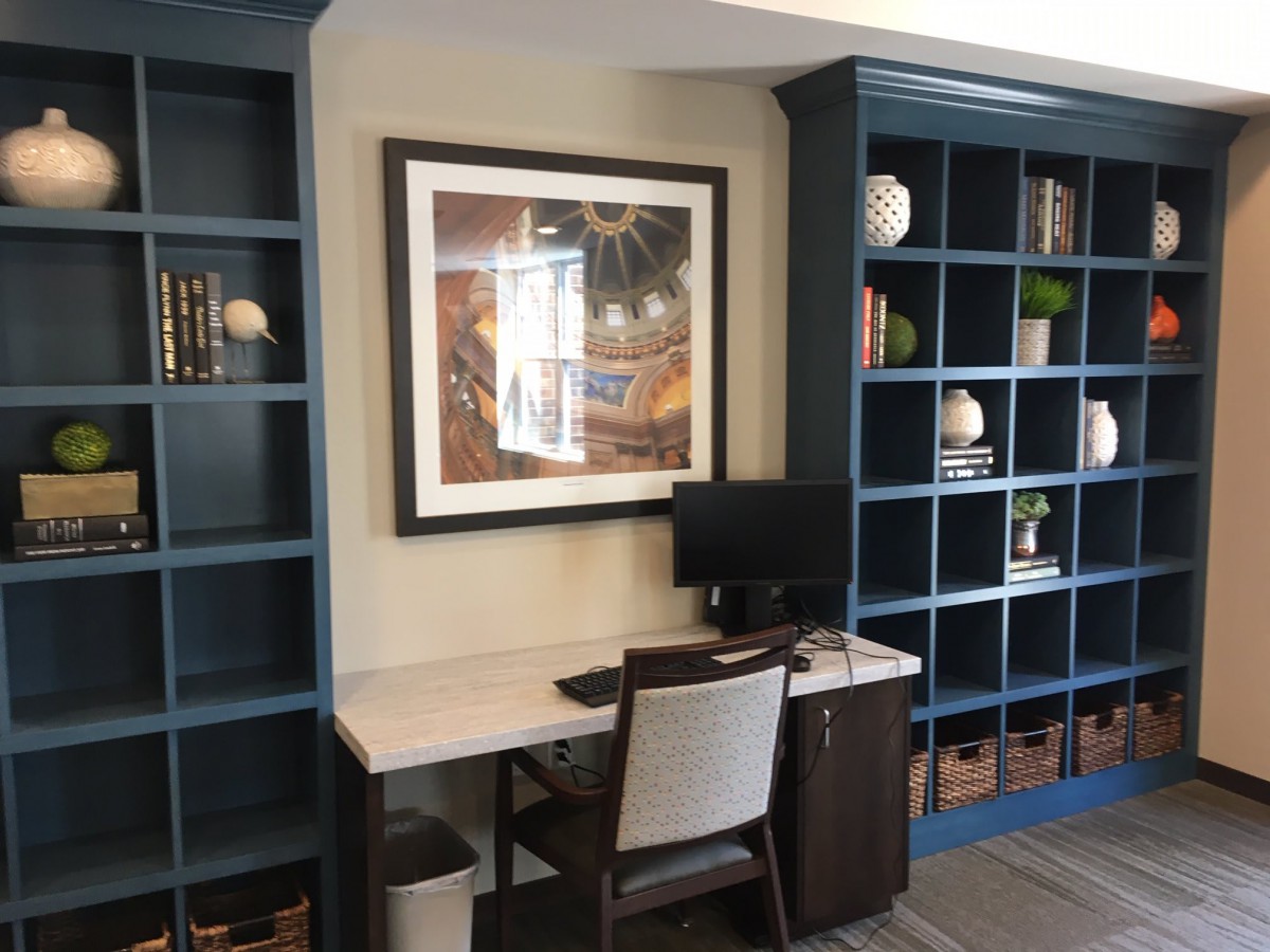 A home office setup with a desk, chair, computer, and bookshelves adorned with various decorations and books.