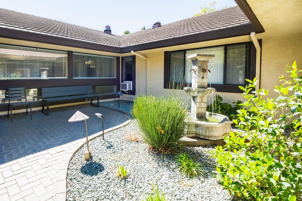 A modern courtyard featuring a decorative fountain surrounded by landscaped gardens.
