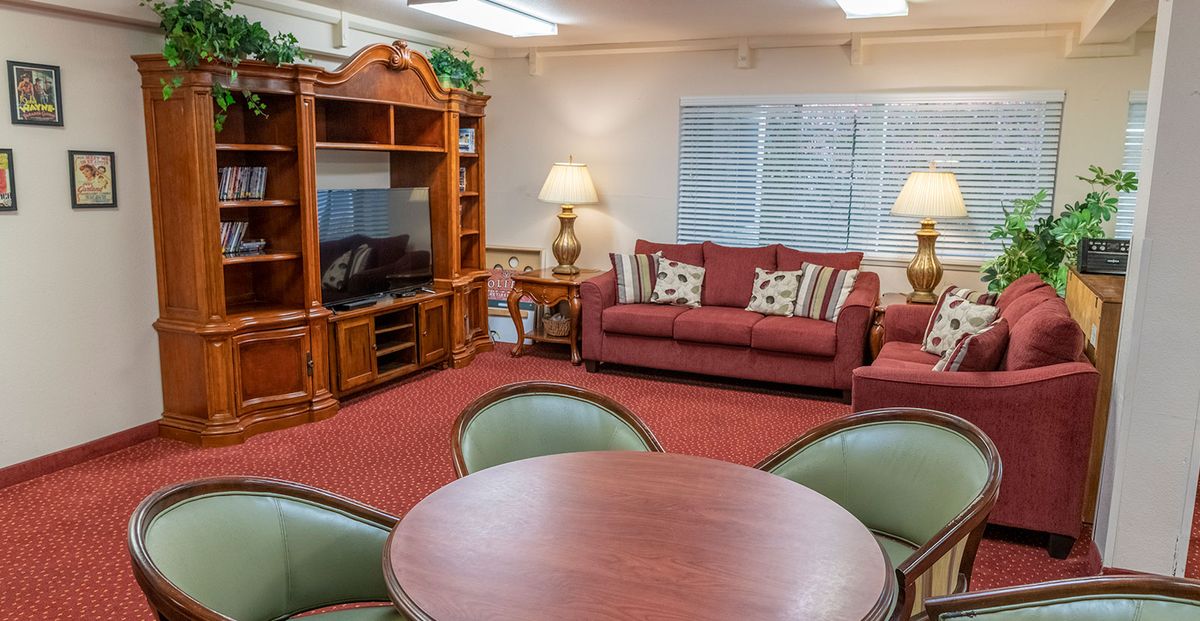 A cozy living room with a sofa, television, table, and lamps.