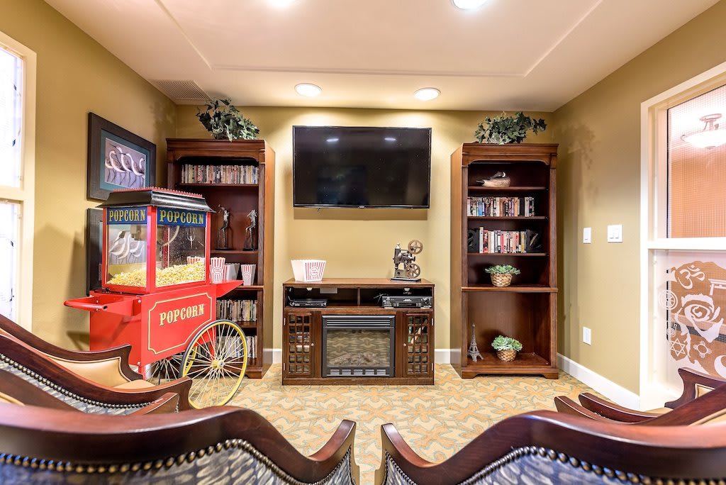 A cozy home theater setup featuring a television, bookshelves, and a popcorn machine.