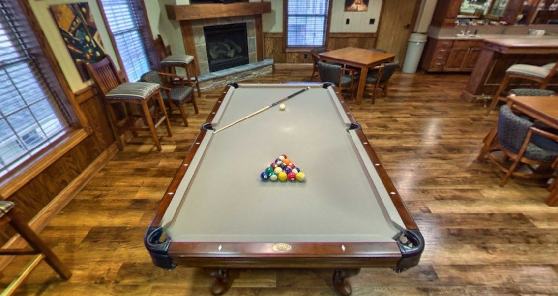 A cozy game room featuring a pool table with a cue stick and racked balls ready for play.