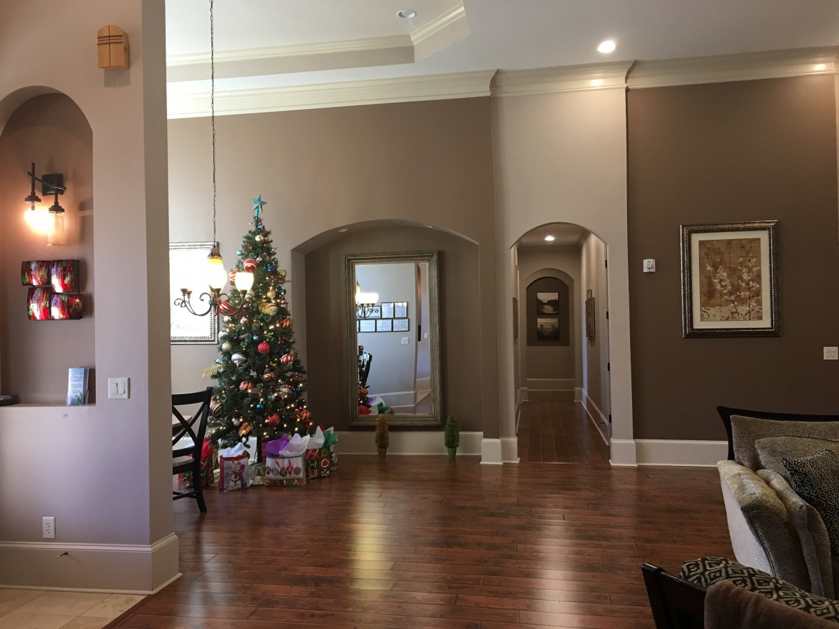 A cozy living room decorated for Christmas with a tree and presents beneath.