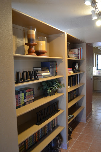 A cozy bookshelf displaying books, decorative candles, and inspiring words.