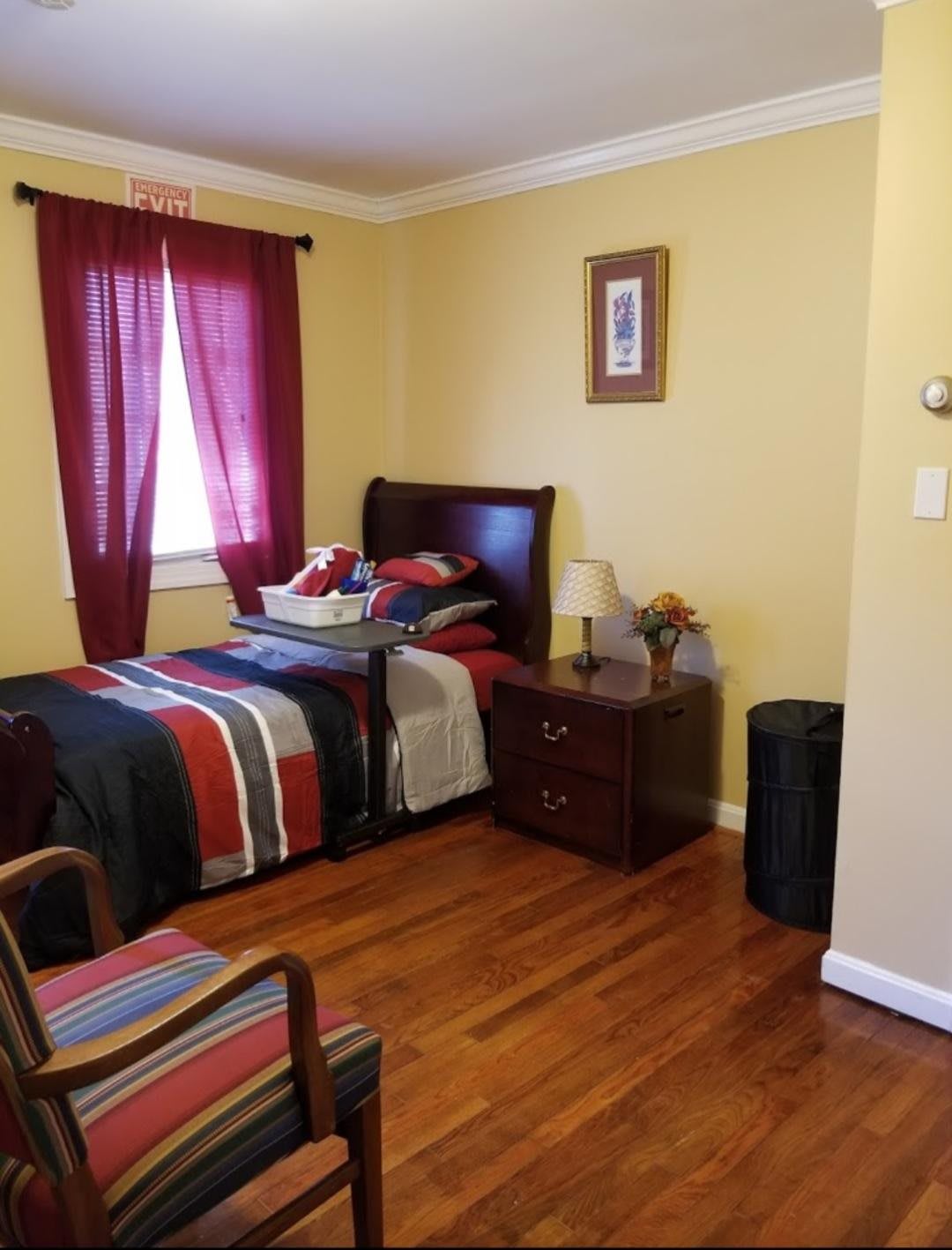 A cozy bedroom with a single bed, nightstand, and wooden floors.