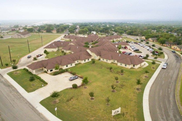 Aerial view of a residential complex with ample green spaces and parking areas.