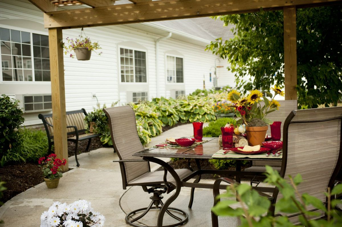 A cozy patio setup with a dining table surrounded by garden plants and flowers.