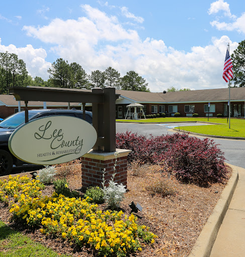 A welcoming entrance with vibrant flowers and a flag flying at a facility.