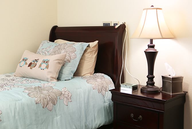 A cozy bedroom setup with a neatly made bed and a lamp on the nightstand.
