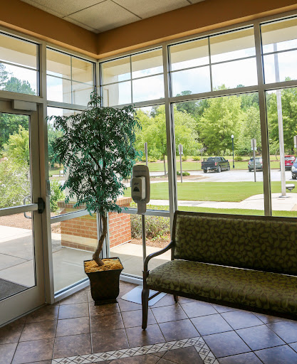 A bright and inviting lobby space featuring a comfortable green couch and a potted plant.