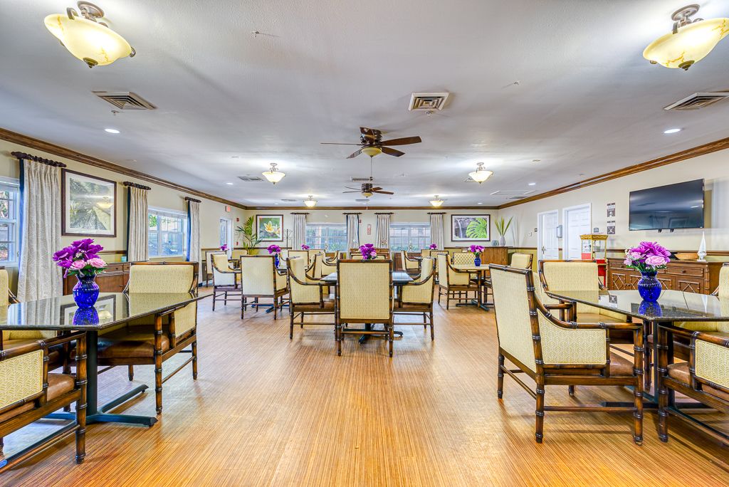 Spacious dining room with neatly arranged tables and chairs, featuring wooden flooring and ample lighting.
