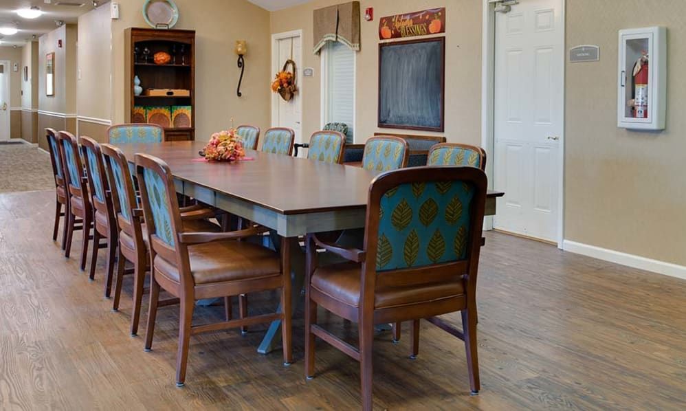 A spacious dining room with a large table surrounded by chairs, featuring warm and inviting decor.