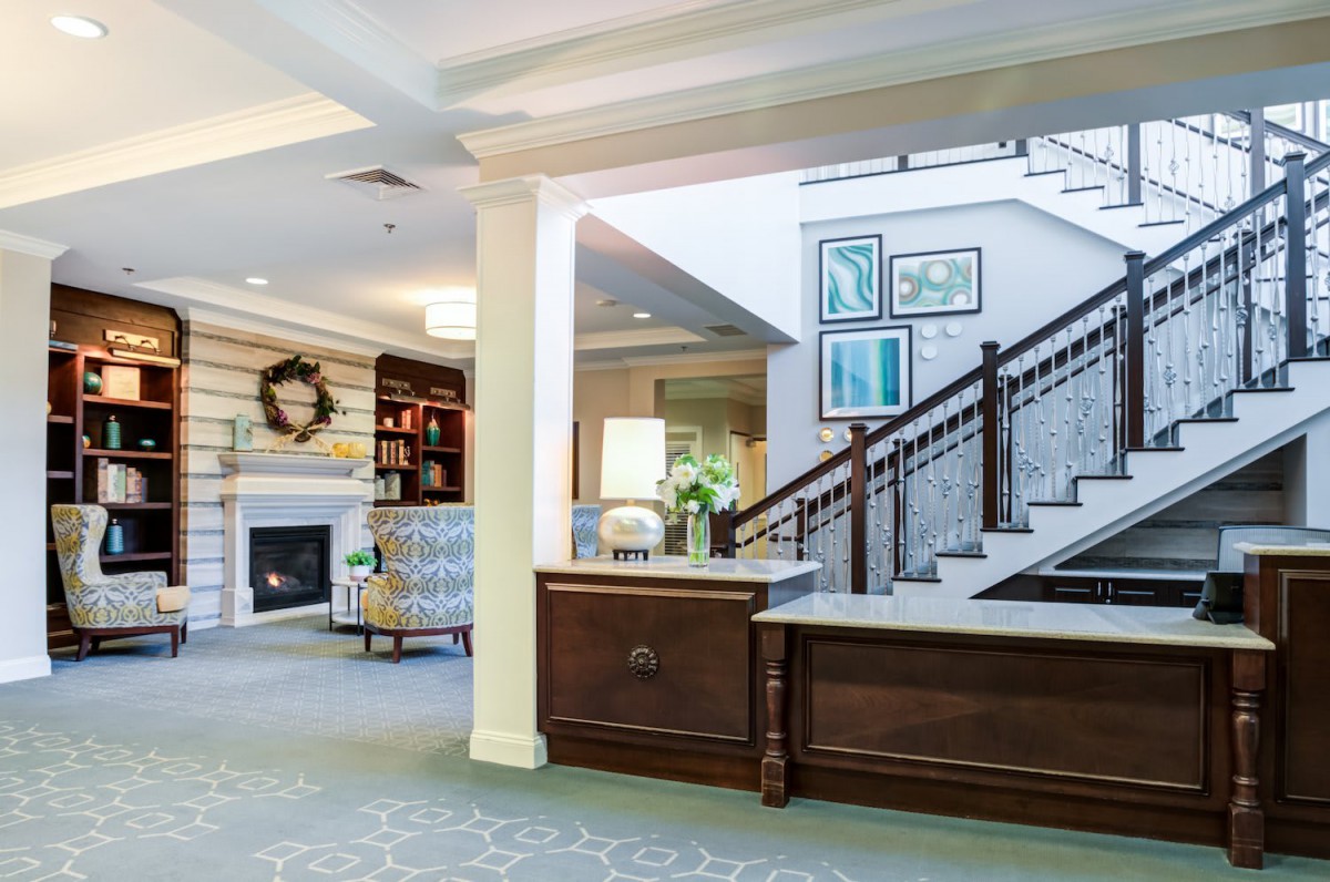 A spacious and elegantly decorated lobby area featuring a reception desk, staircase, and cozy seating.