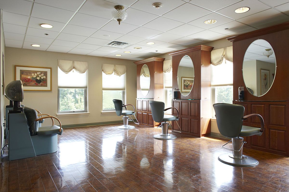 An empty hair salon with styling chairs and large mirrors by the windows.