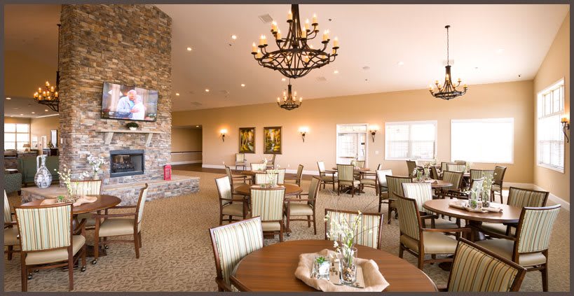 A spacious dining area featuring elegant chandeliers, comfortable seating, and a cozy fireplace.