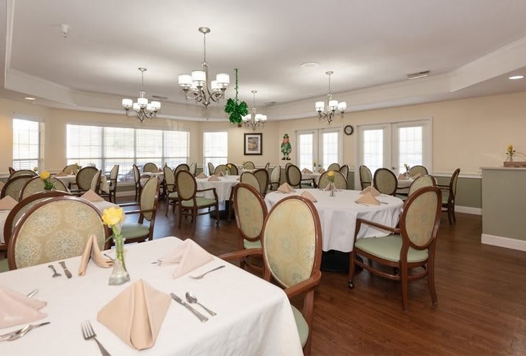 An elegant dining room with neatly arranged tables and chairs, decorated with chandeliers.