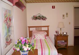 A cozy bedroom with a pastel-colored bedspread and floral decorations.