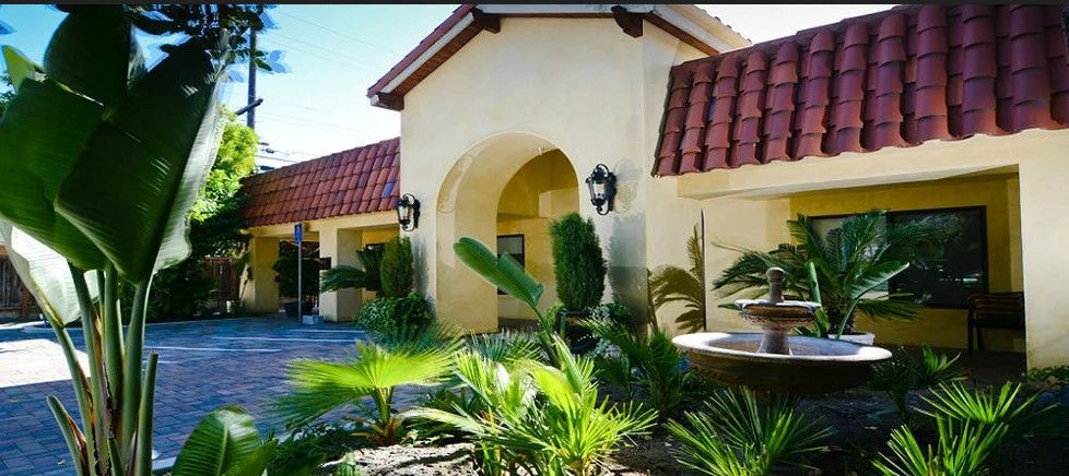 A Mediterranean-style house with a red-tiled roof and lush landscaping.