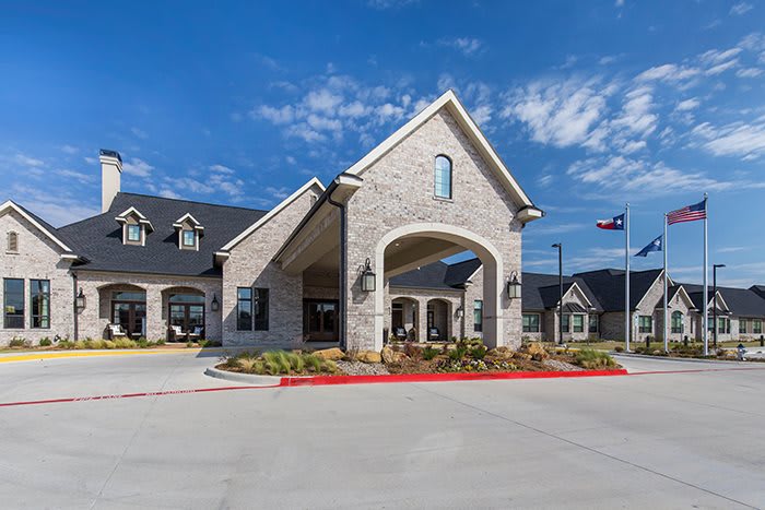 A modern stone building with an arched entrance under a partly cloudy sky.