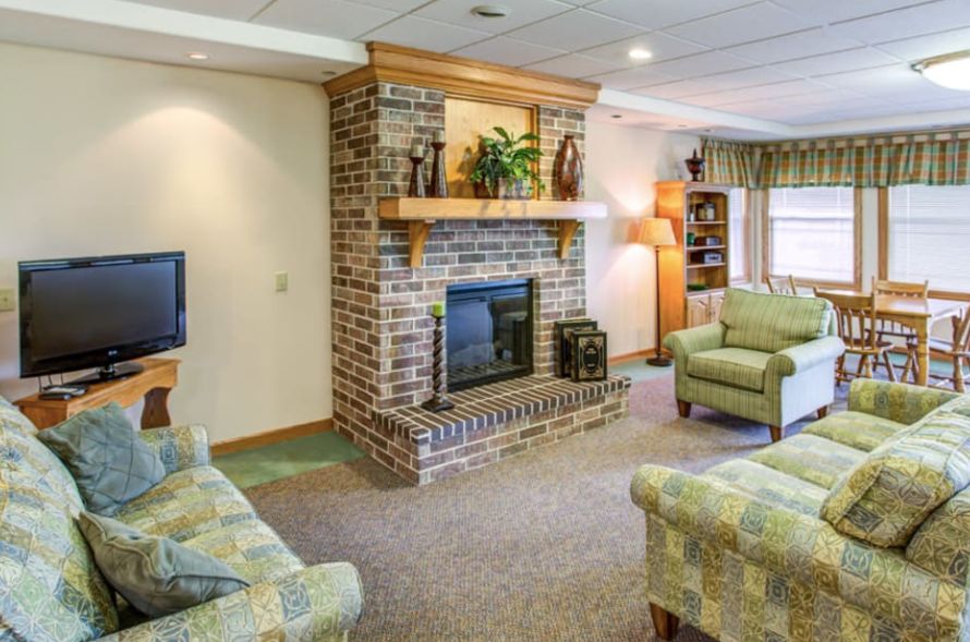 A cozy living room with a brick fireplace, comfortable sofas, and warm lighting.