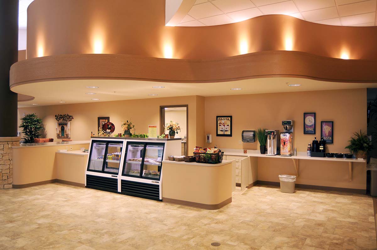A modern cafe interior featuring a beverage station and refrigerated display counters.