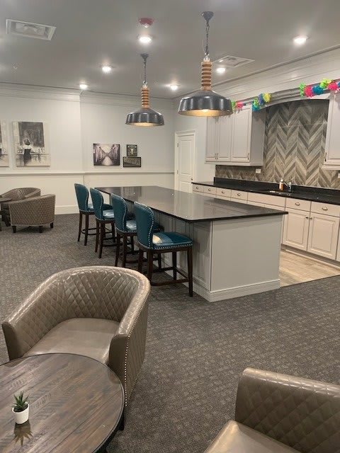 A modern kitchen with a spacious countertop and bar stools, complemented by stylish pendant lighting.
