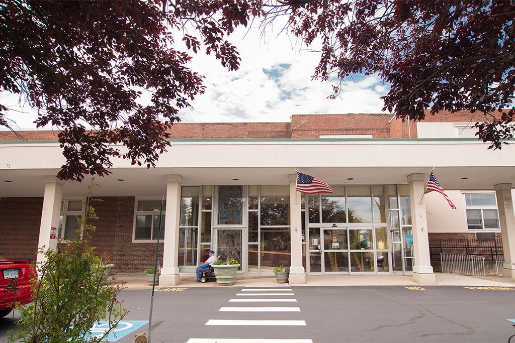 Entrance of a modern building with glass doors and an American flag.
