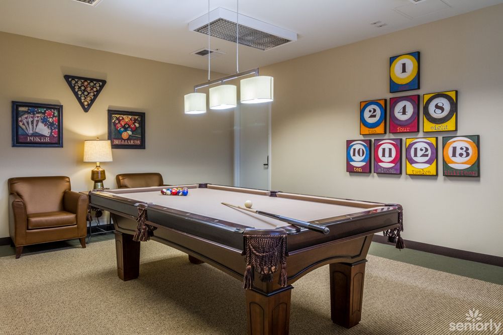 A stylish game room featuring a billiards table with modern lighting and decorative artwork on the walls.