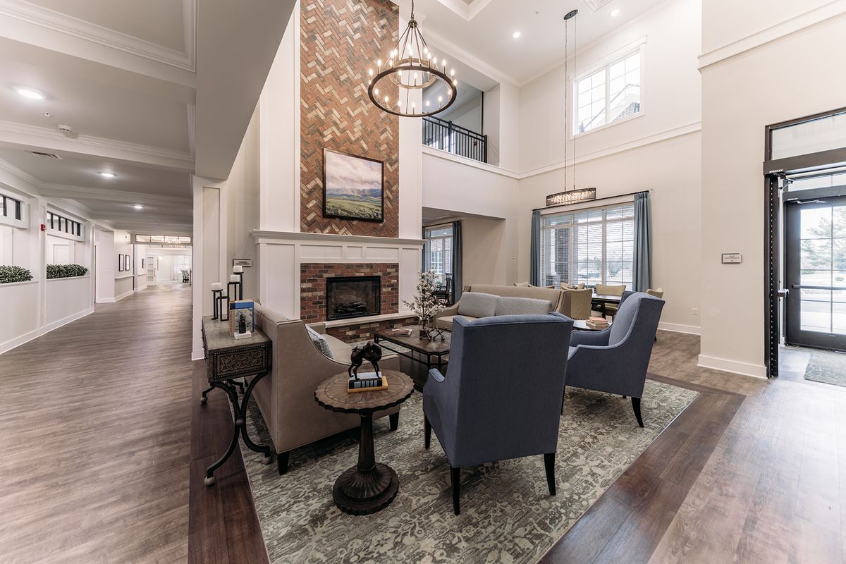 A modern living room with a high ceiling, featuring a cozy fireplace and elegant furnishings.