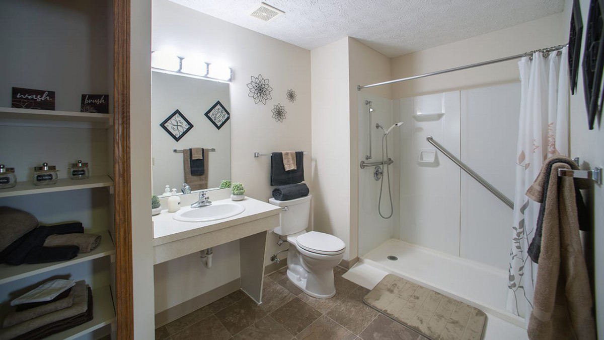 A clean and modern bathroom with a walk-in shower, vanity, and toilet.