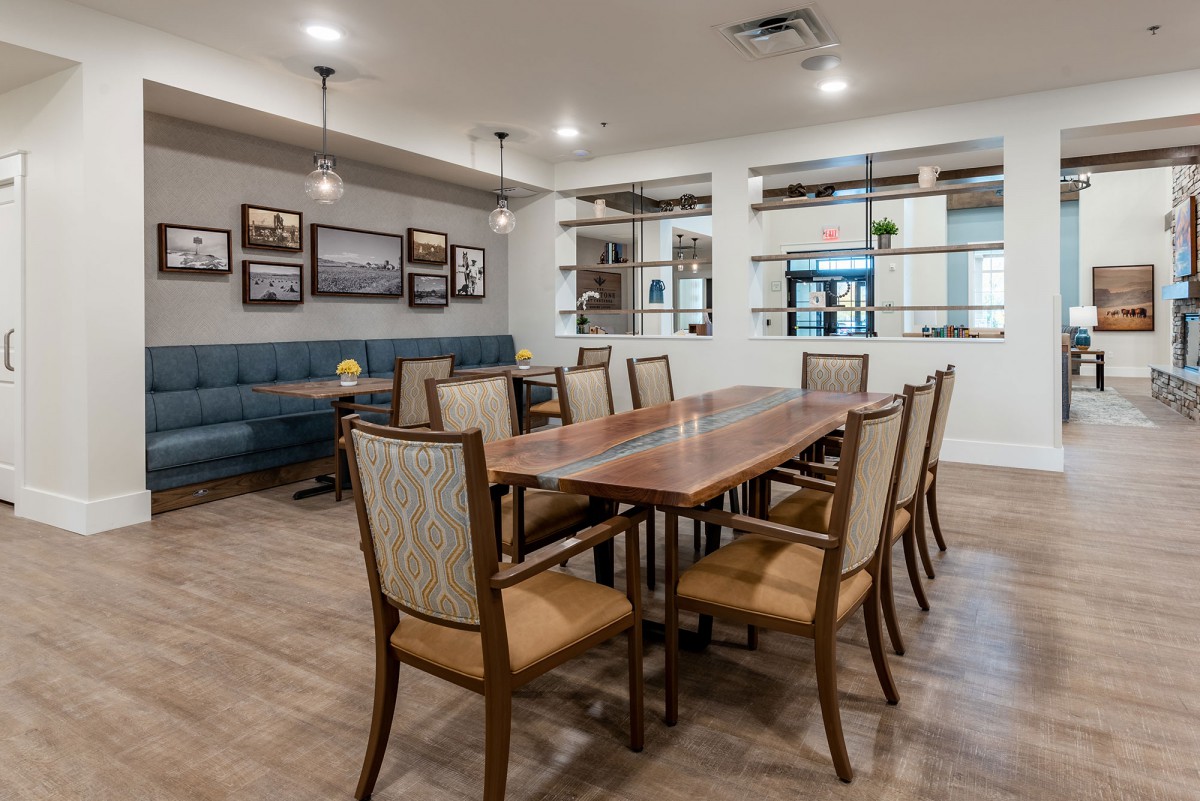 A modern dining room with a large wooden table surrounded by chairs, adorned with stylish lighting and wall art.