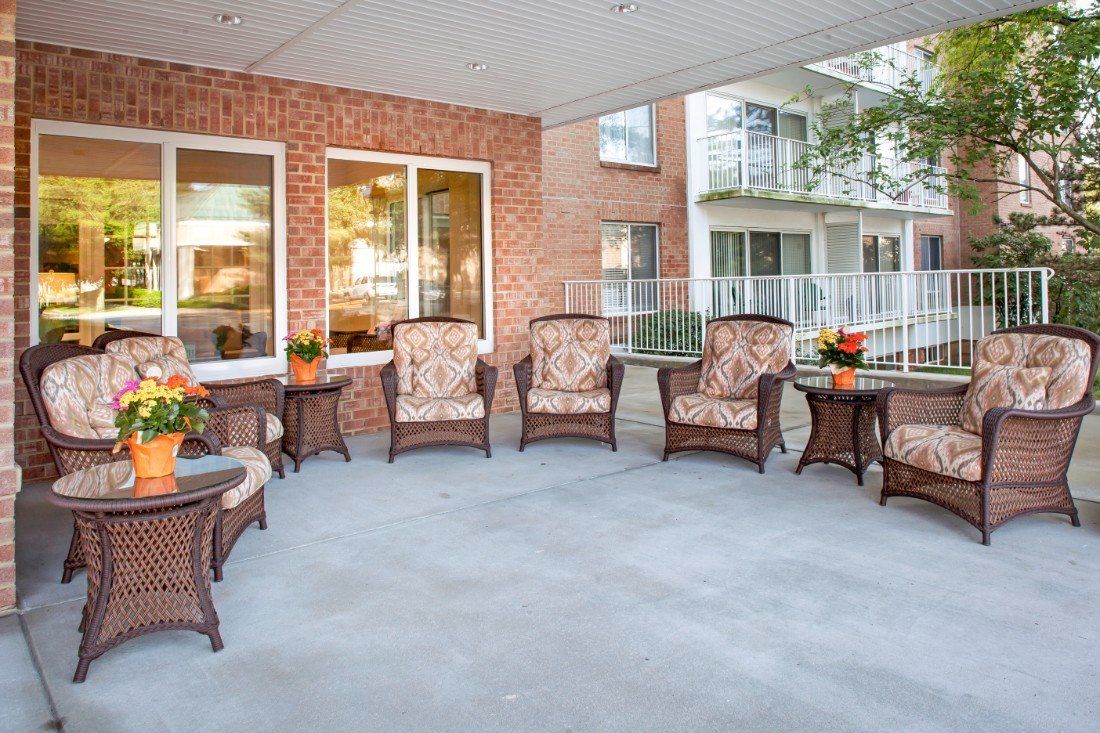 A cozy outdoor patio with wicker chairs and small tables, set against a brick wall.