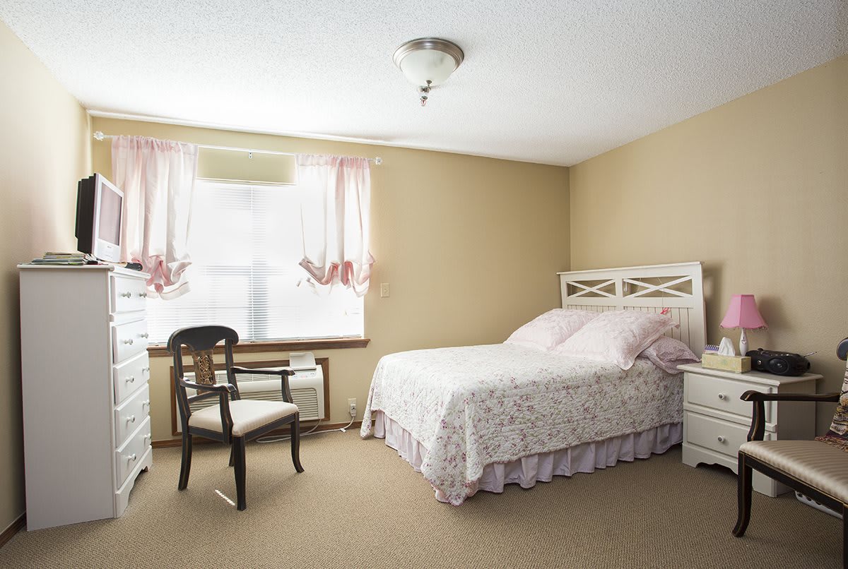 A cozy bedroom with a single bed, chair, and decorated window.