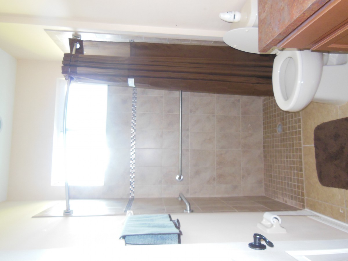 A clean and well-lit bathroom with a shower, sink, and towel.