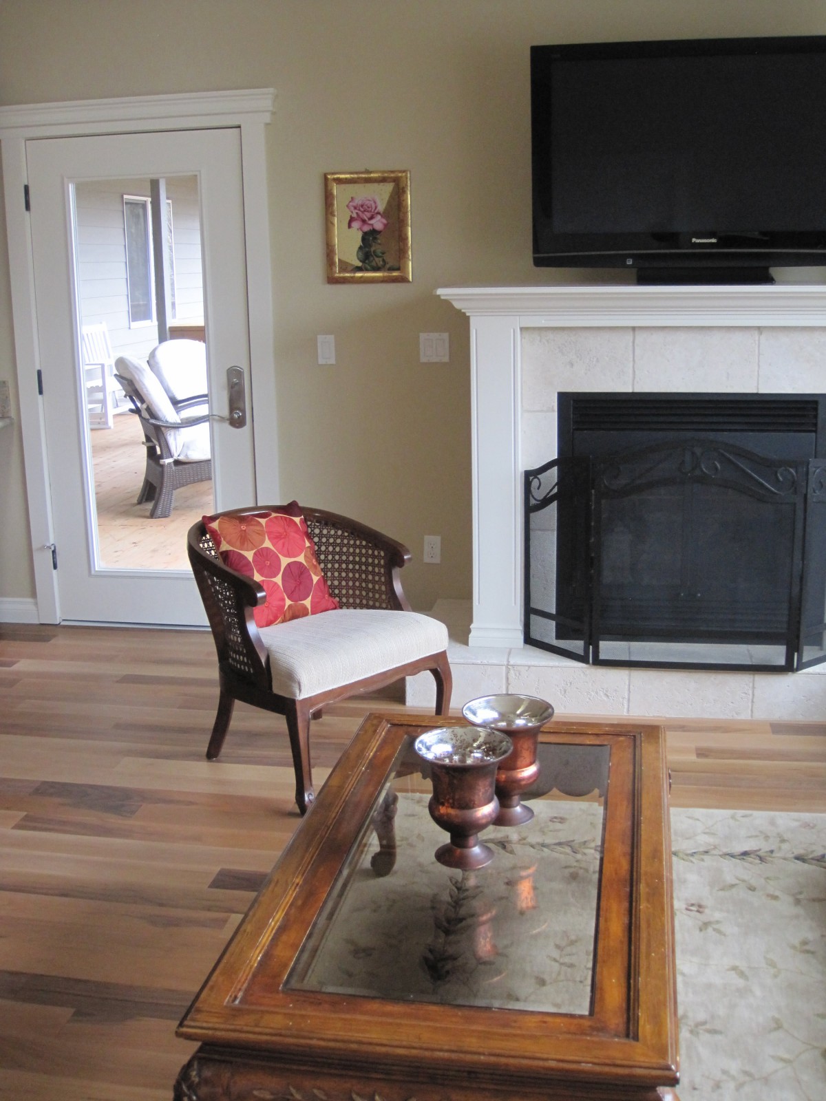 A cozy living room featuring a fireplace, a stylish chair with a red cushion, and a television mounted above the mantel.