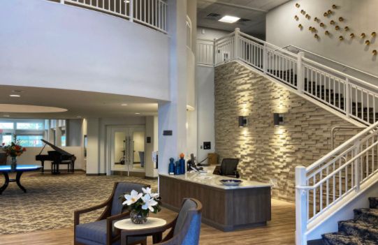 A modern lobby area with a reception desk, seating, and a stylish staircase.