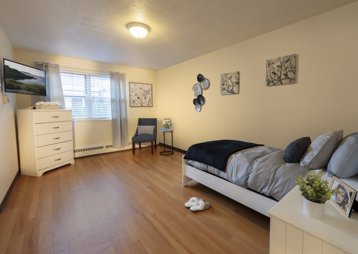 A neatly arranged bedroom with a single bed, dresser, and chair.