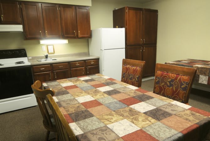 A cozy kitchen and dining area with a colorful tablecloth and wooden cabinetry.