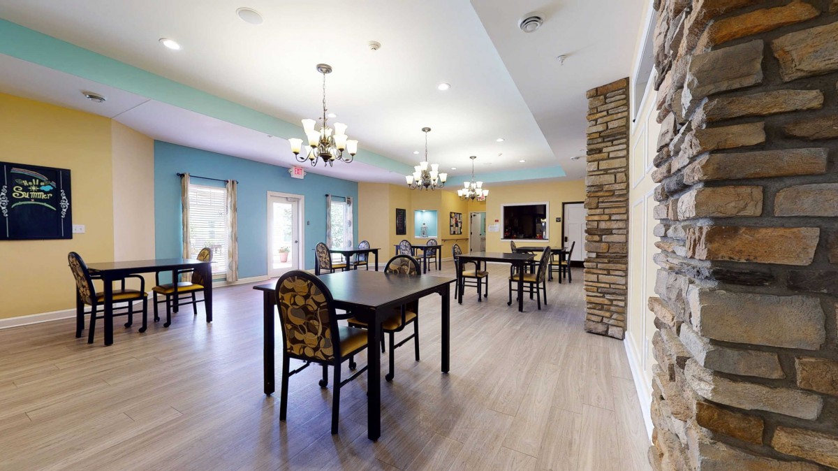A spacious dining room with multiple tables, chairs, and elegant chandeliers.