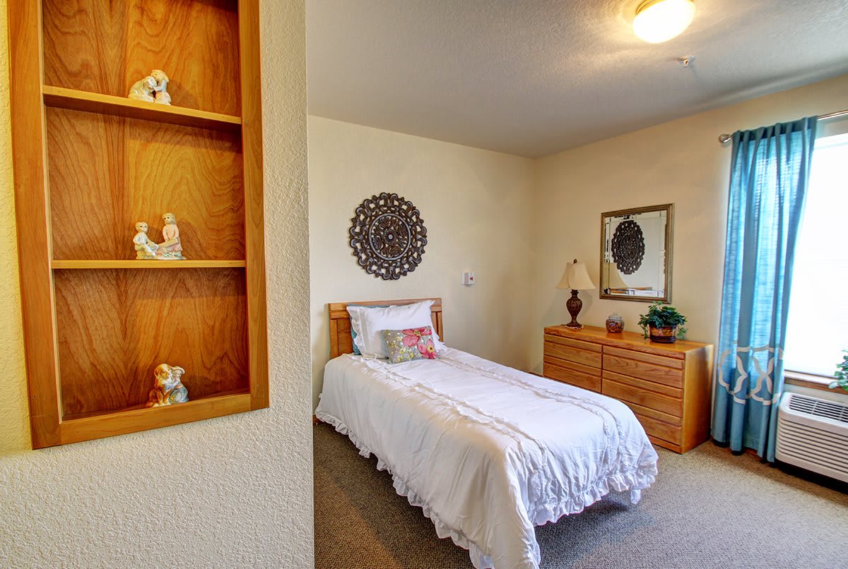 A cozy bedroom featuring a single bed with white bedding, wooden furniture, and minimalist decor.