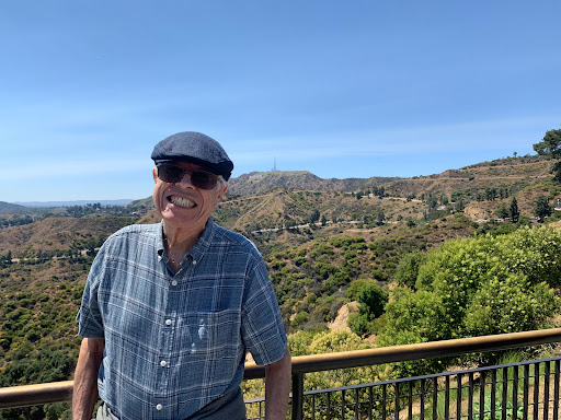 A cheerful man enjoying a sunny day with a beautiful mountain backdrop.